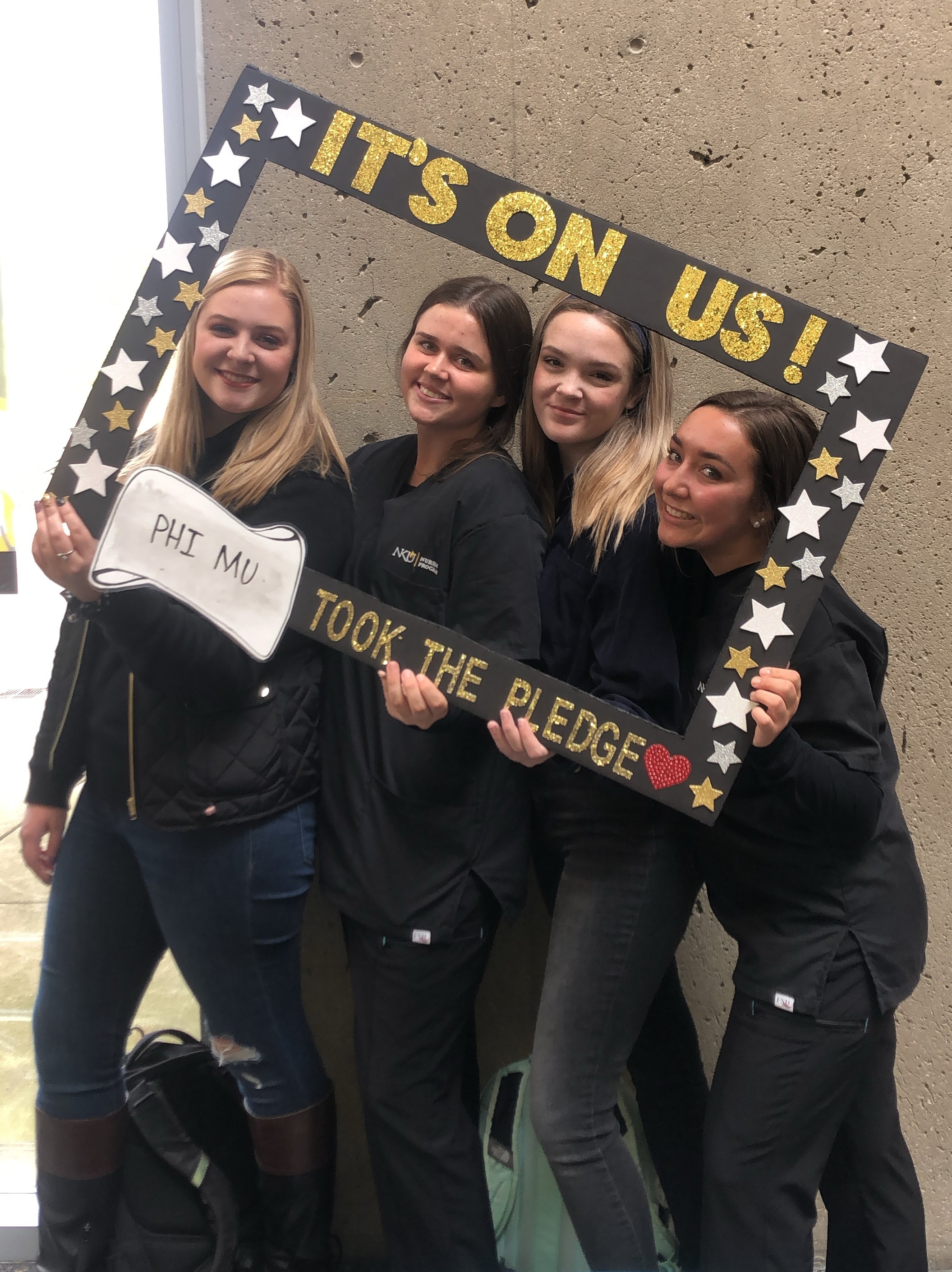 Four student members of Phi MU sorority holding photo frame with It's On Us pledge in SU