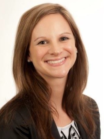 Photo of a brown haired, Caucasian, young professional woman, smiling, in professional attire.