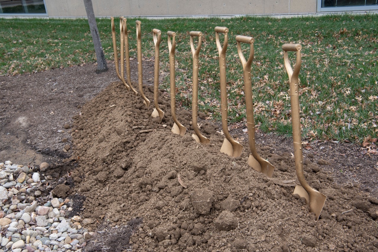 A picture of 10 golden shovels in a pile of dirt