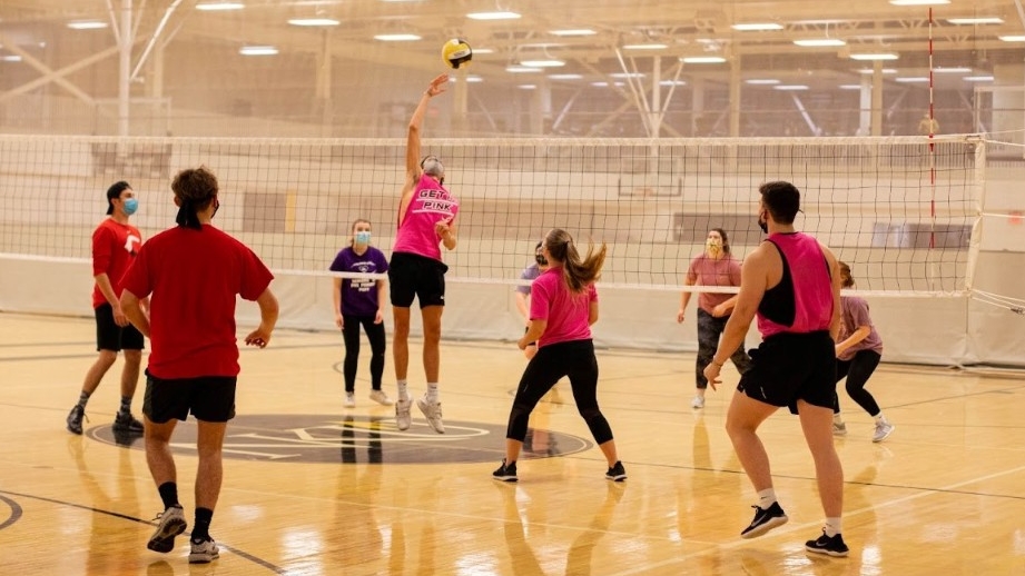 Students playing volleyball on an indoor volleyball court