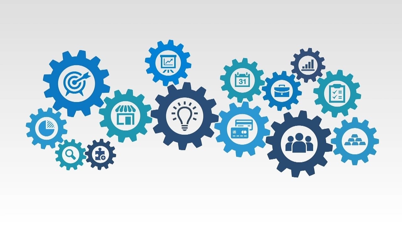 A graphic of various size gears connected together with clip graphics of people, calendars, and other business related items