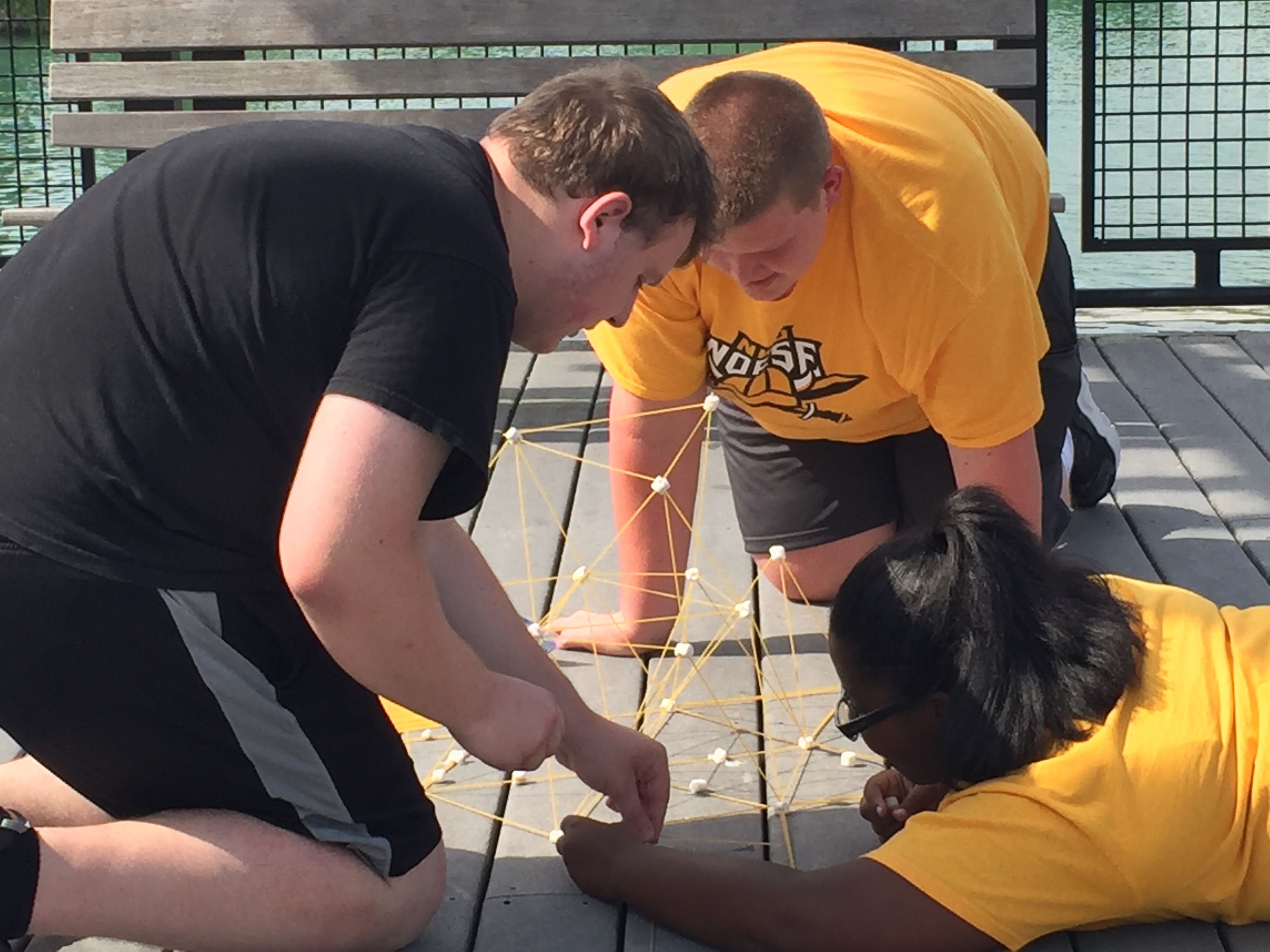 Three students working on a string project outside