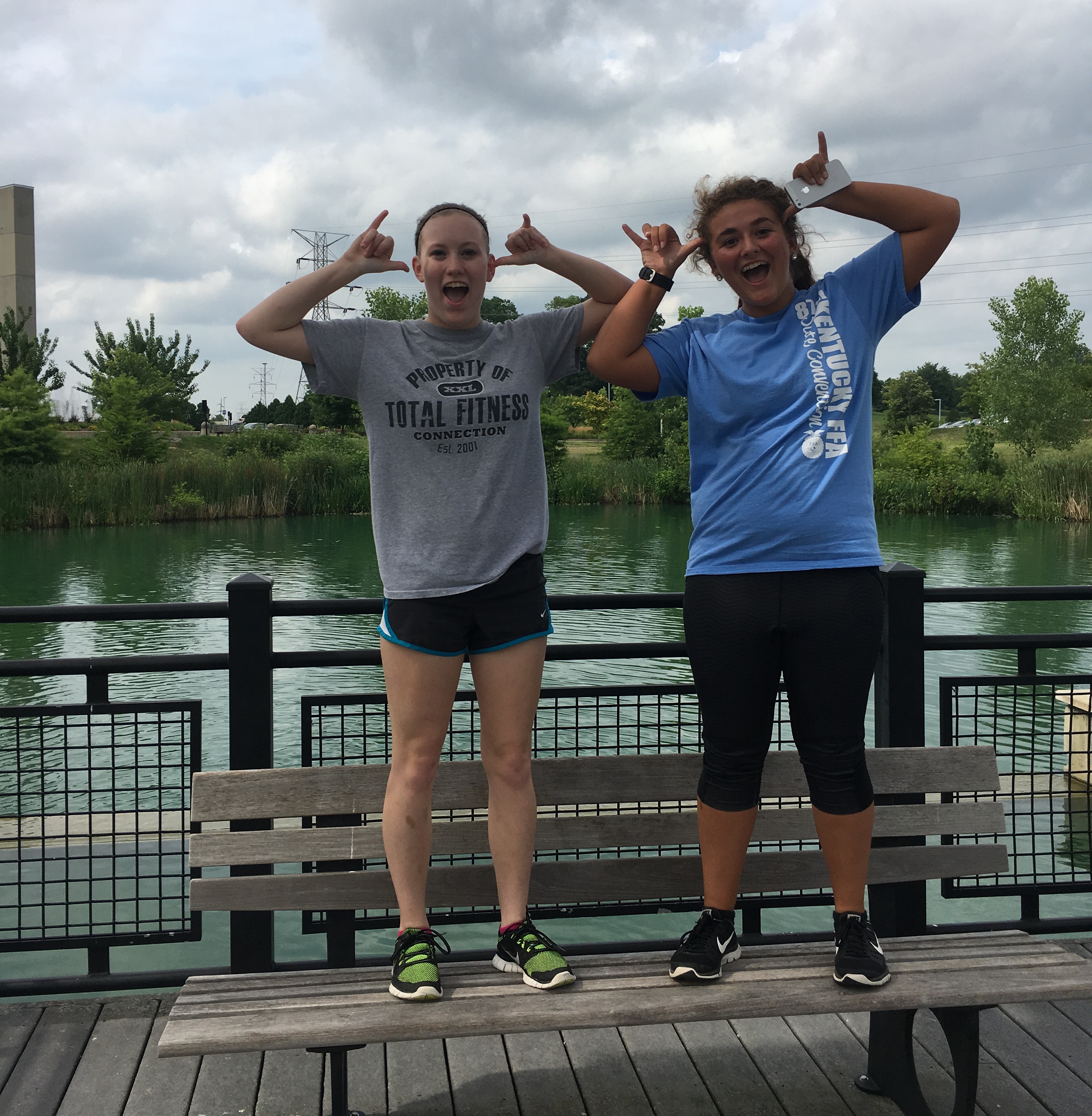 Two students standing on benches by Loch Norse