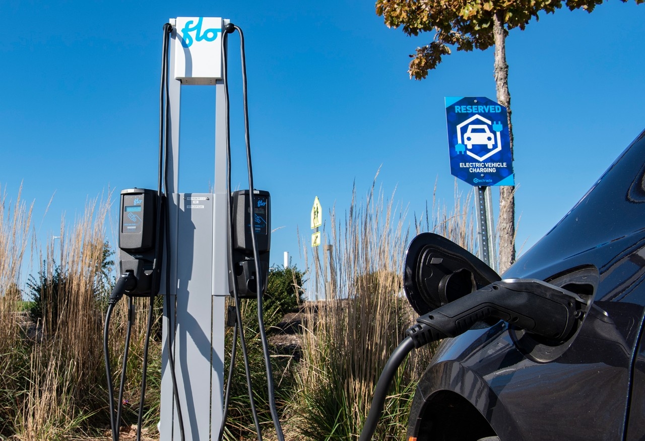 Picture of a Electric vehicle plugged into an electric charging station on a clear day