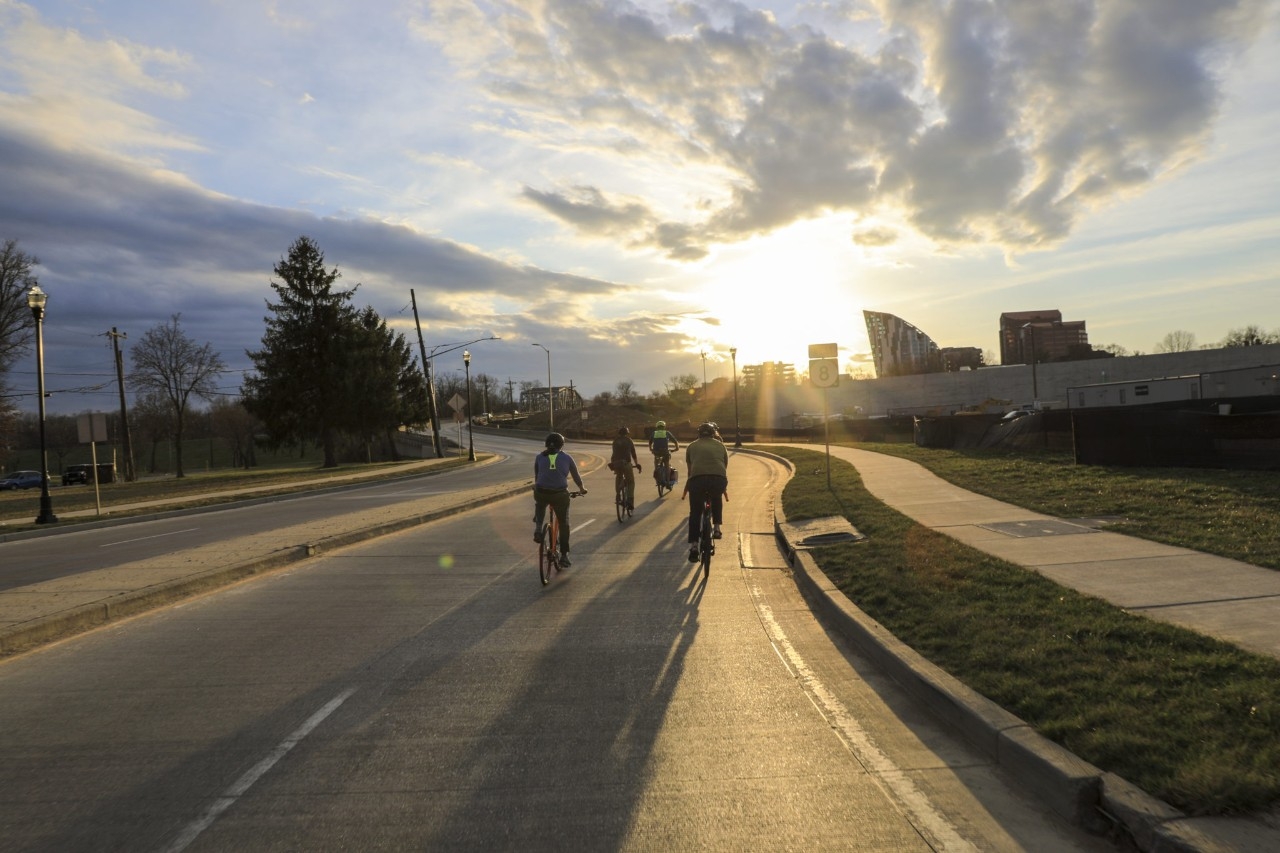 4 people ride bikes on a trail during sunset