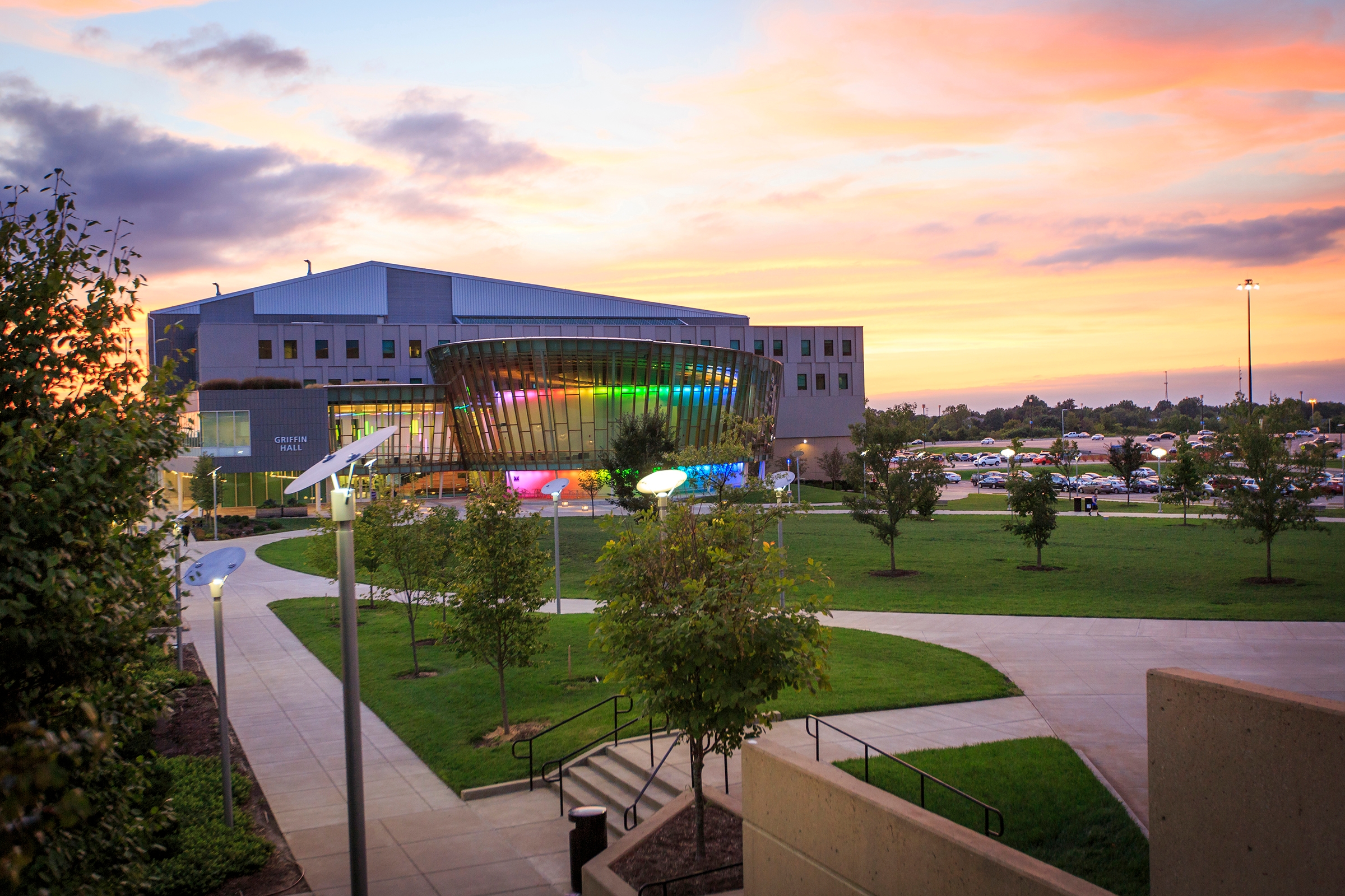 Griffin Hall pictured in front of a sunset with colorful lights surrounding the building's exterior
