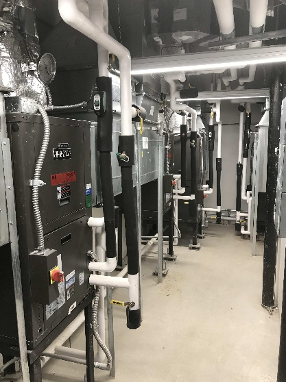 Geothermal Well Field and Water System Pipes brightly lit in facilities room
