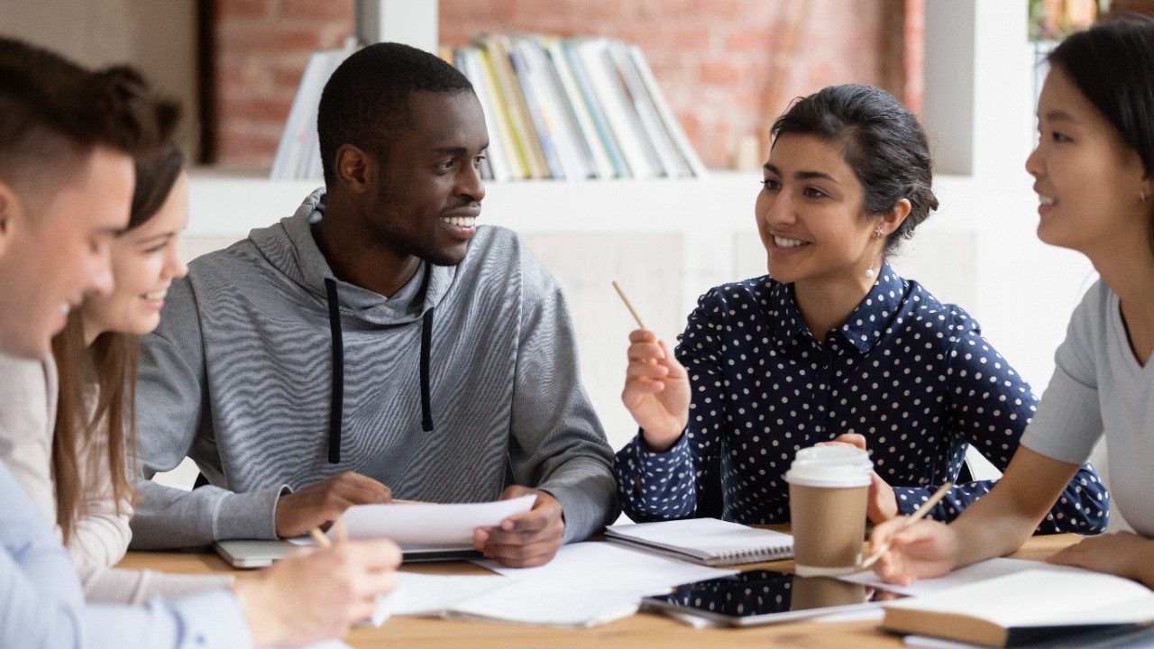 Group of students sitting a table talking to each other.