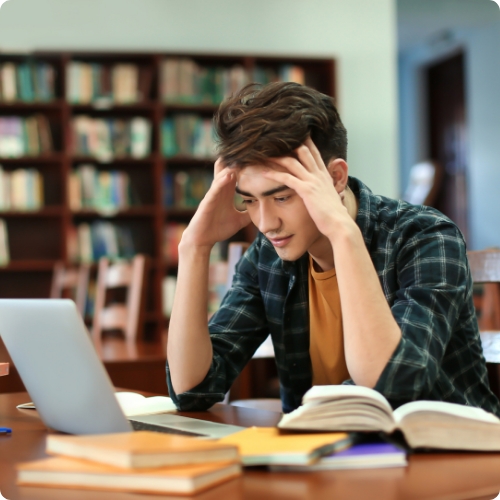 A male student in a library looking frustrated