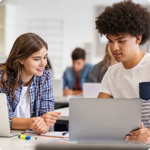 Two tudents looking at a laptop in a classroom