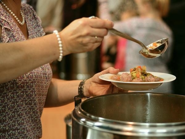 A person is serving themselves soup at a soup kitchen.