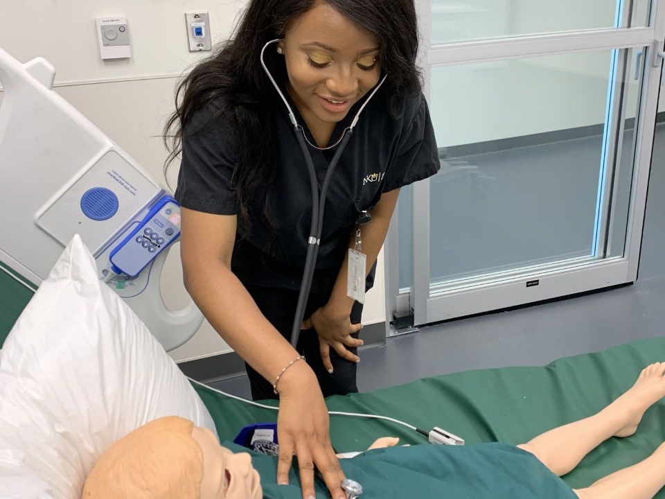Nursing student demonstrating how to listen to a heart with a stethoscope on a dummy. 