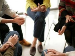 Five people seated in a circle during a group therapy session.