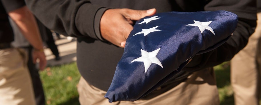 Close-up image of someone holding a folded United States flag.