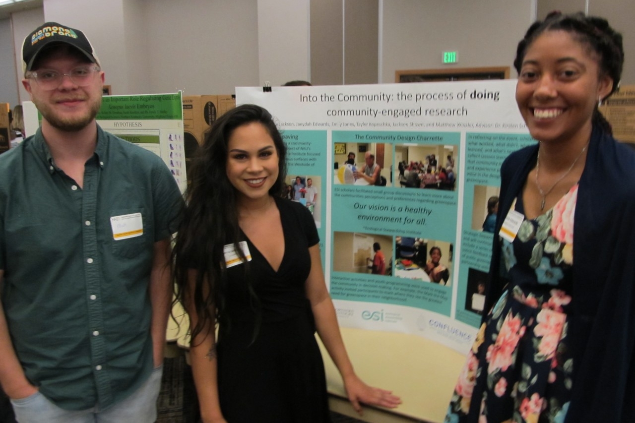 Diverse students proudly present their summer research poster.