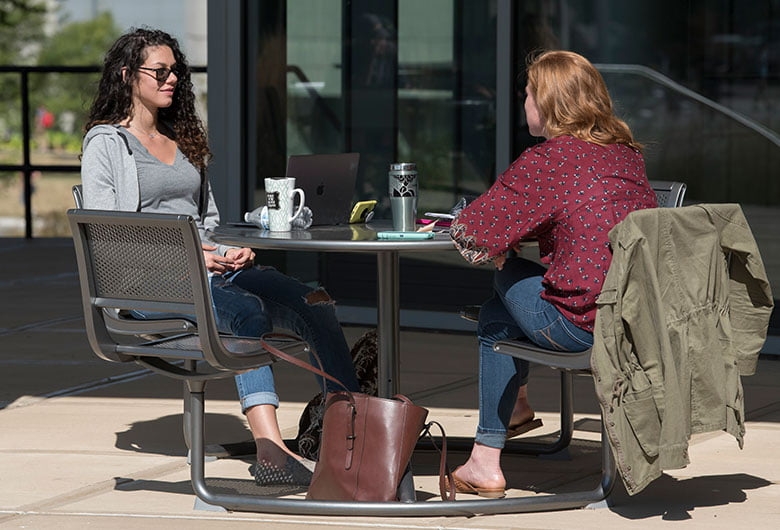Two students sitting a table outside on NKU's campus.
